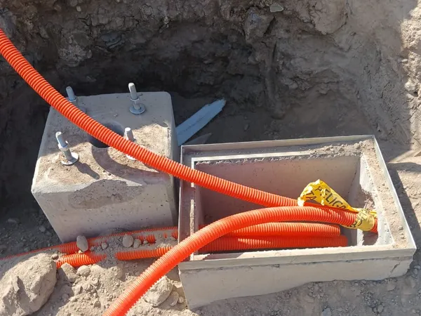 Registro eléctrico con ducto naranja al fondo de la excavación