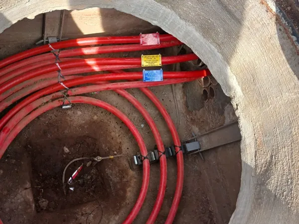Pozo de visita con los ductos rojos peinados y sujetos a la pared