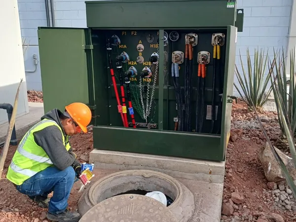 Técnico conectando el gabinete de media tensión junto al registro eléctrico