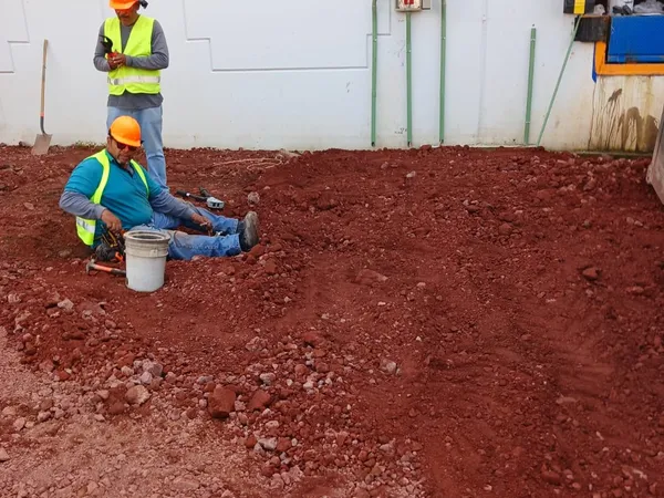 Cuadrilla trabajando sobre el terreno preparado junto al muro de la nave