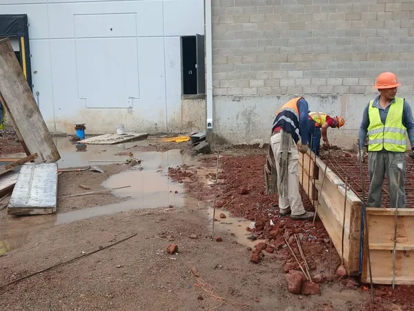 Trabajadores en el área de colado junto a la fachada del edificio