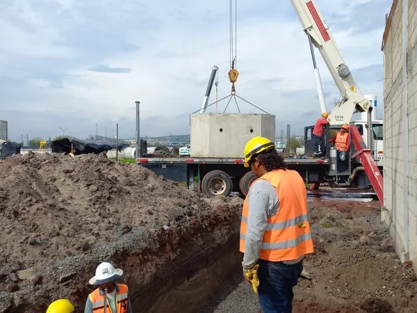Grúa y cuadrilla trabajando sobre la excavación abierta