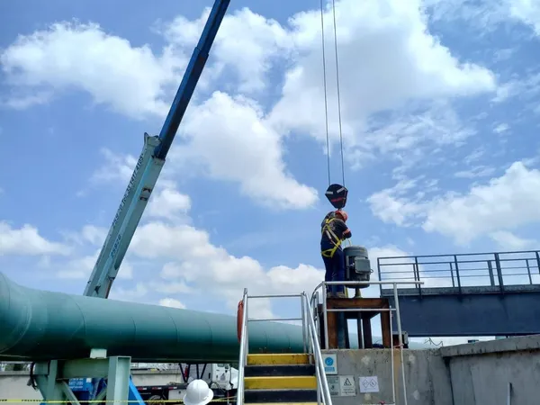 Trabajador subiendo la escalera de acceso junto a la tubería de conducción