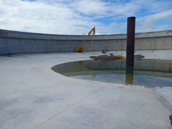 Interior de un tanque circular de concreto durante la obra, con excavadora al fondo