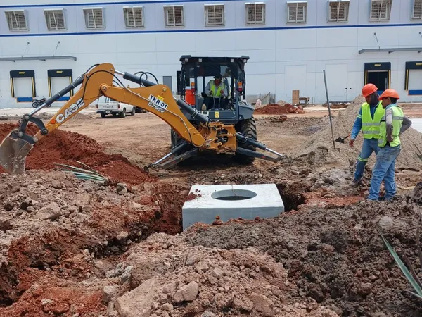 Excavadora trabajando junto a un registro prefabricado recién colocado