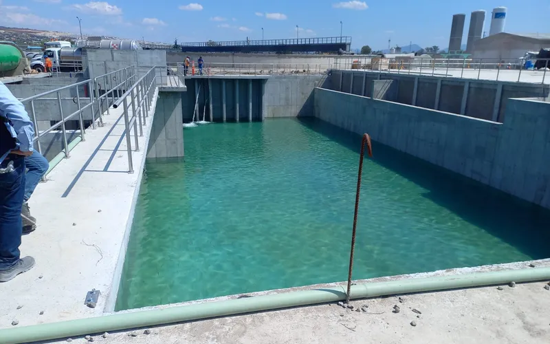 Cárcamo de concreto lleno de agua con compuertas y barandal, obra hidráulica para Conagua