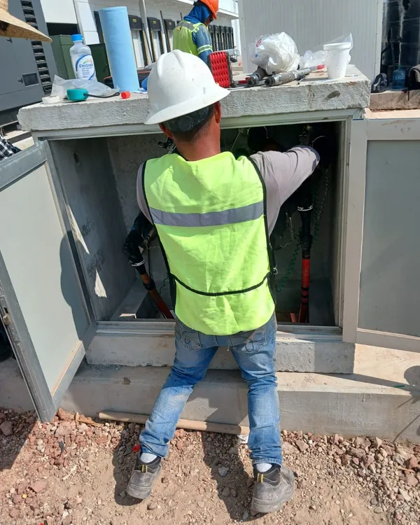 Electricista conectando un tablero de distribución en el exterior de la planta
